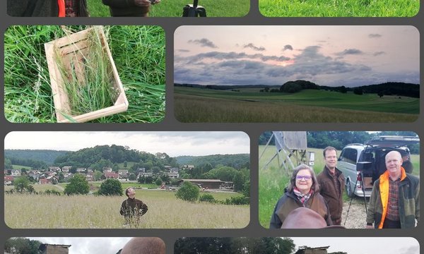 Mehrere Personen steuern und beobachten eine Drohne auf einem Feld. Sie verwenden technische Geräte. Im Hintergrund sind Landschaften, eine Stadt und ein wolkiger Himmel zu sehen.